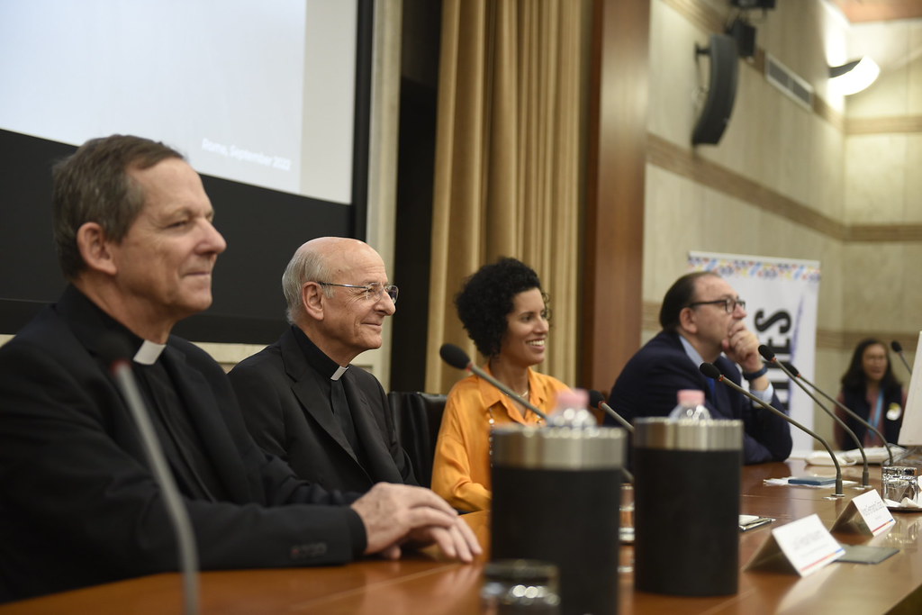 Mesa redonda sobre el origen de BeDoCare, con dos sacerdotes y otros dos participantes durante una conferencia.